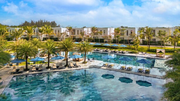 A resort with multiple swimming pools, palm trees, and lounge areas.