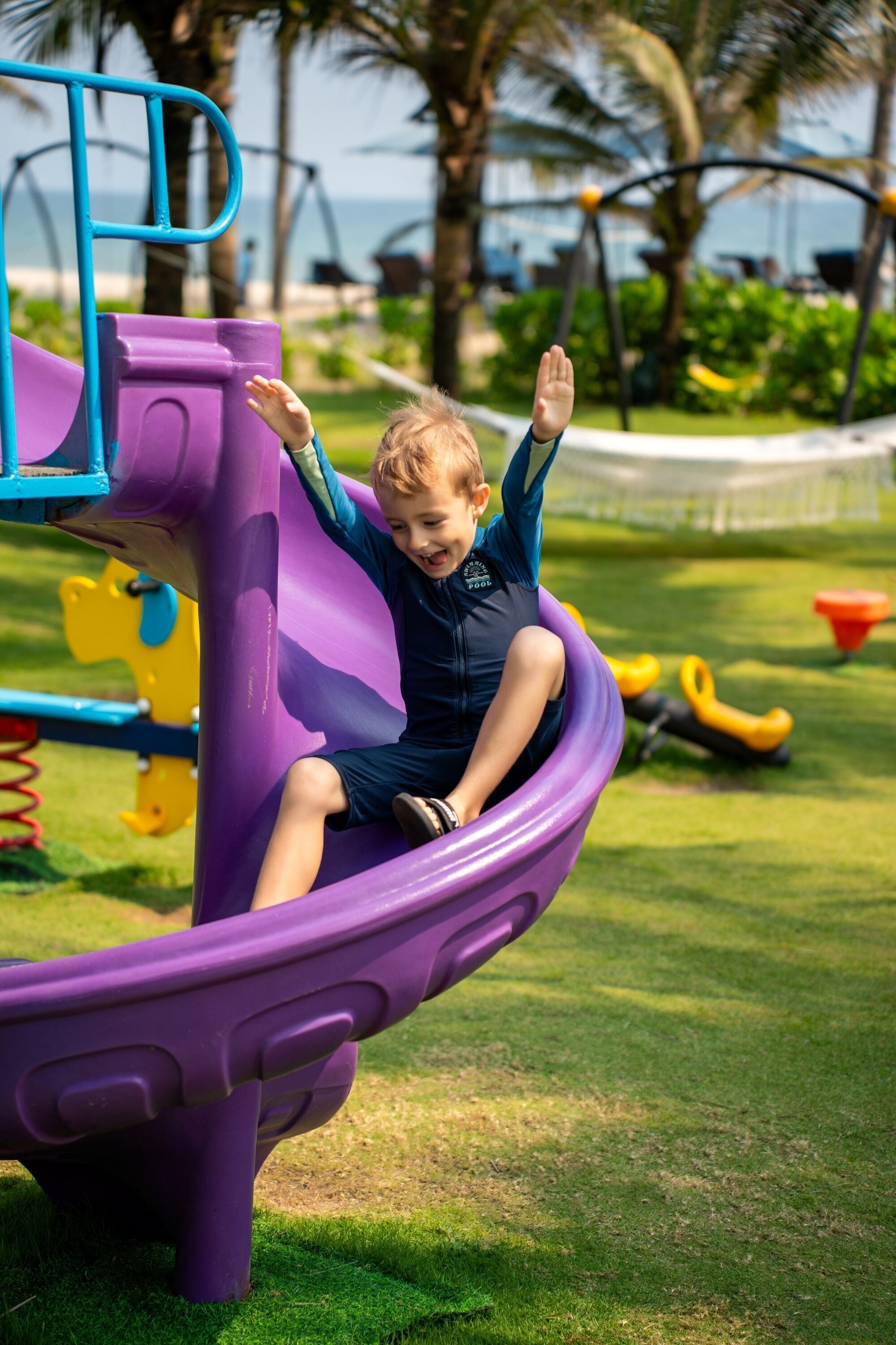 A child on a purple slide at a playground.