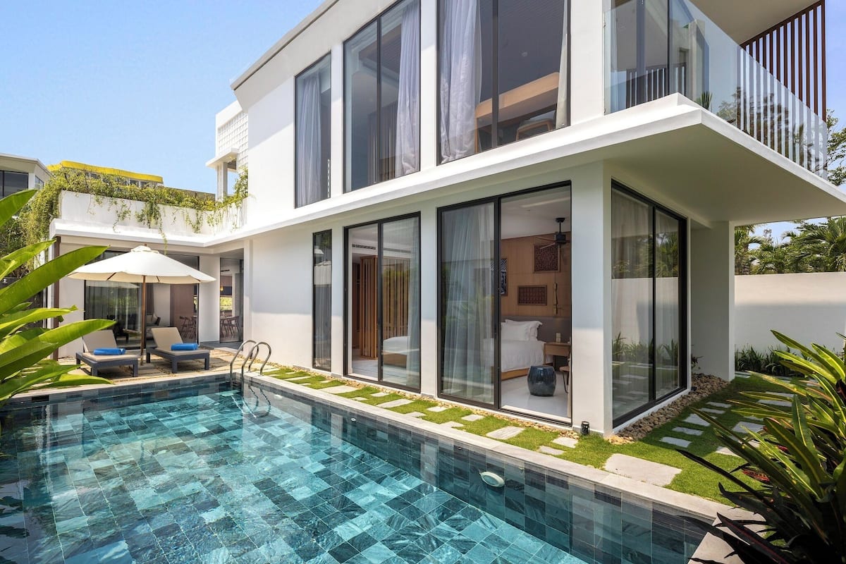A modern house with a swimming pool, large windows, and a balcony.