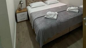 A bedroom with a bed, nightstand, and a window with curtains. - Hotel Princ (Shkodër)