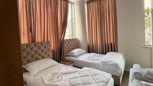 A hotel room with two beds, a wooden headboard, and a small table with towels. - Hotel Princ (Shkodër)