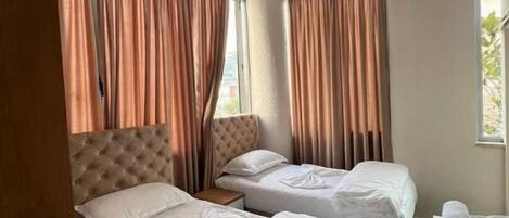 A hotel room with two beds, a wooden headboard, and a small table with towels.