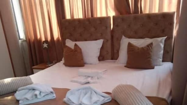 A neatly made bed with a brown headboard, white bedding, and several folded towels. - Hotel Princ (Shkodër)