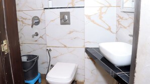 A bathroom with a toilet, sink, and shower. - Hotel Red stone inn (New Delhi)
