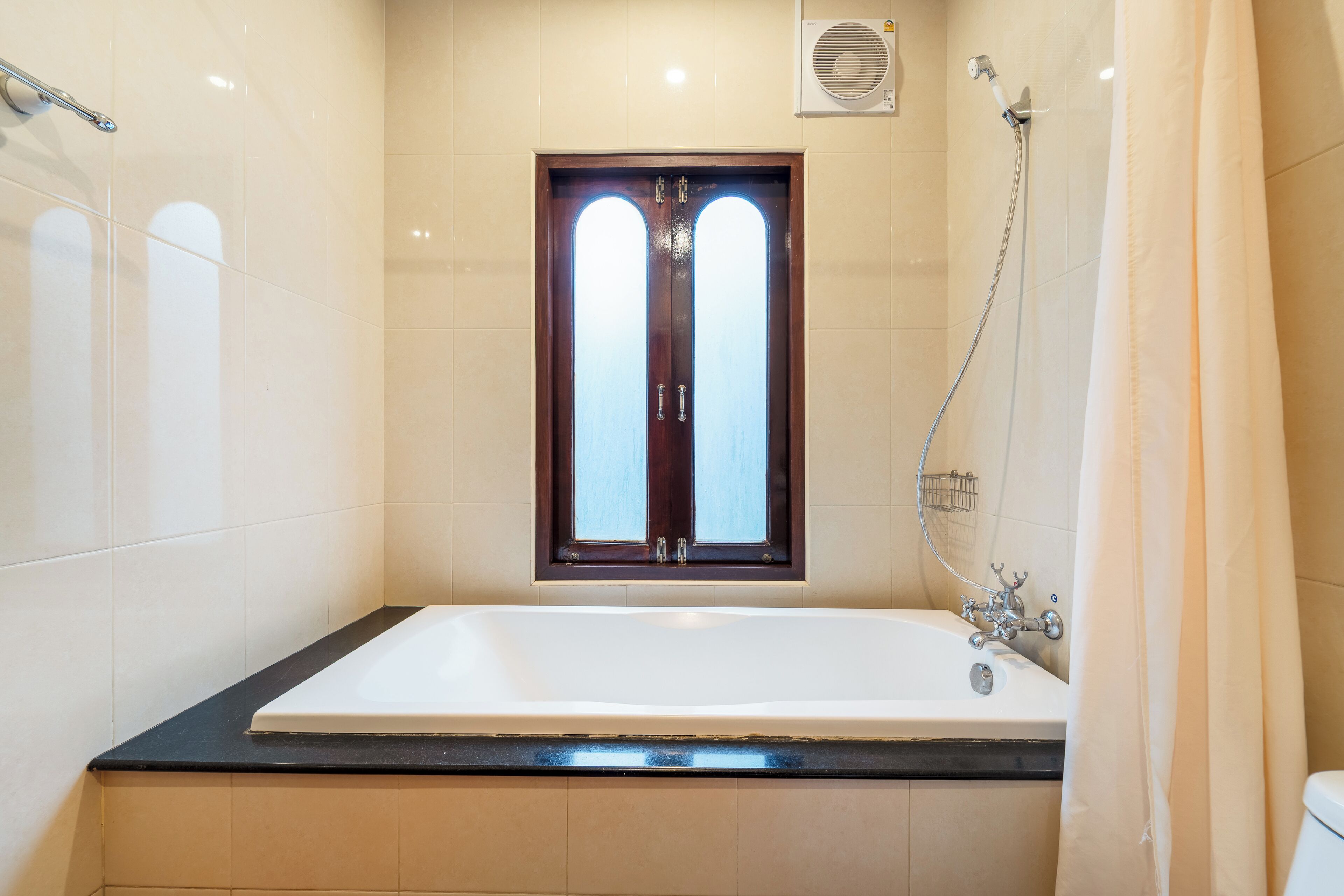 Un baño moderno con una bañera grande, una ventana y una zona de ducha.