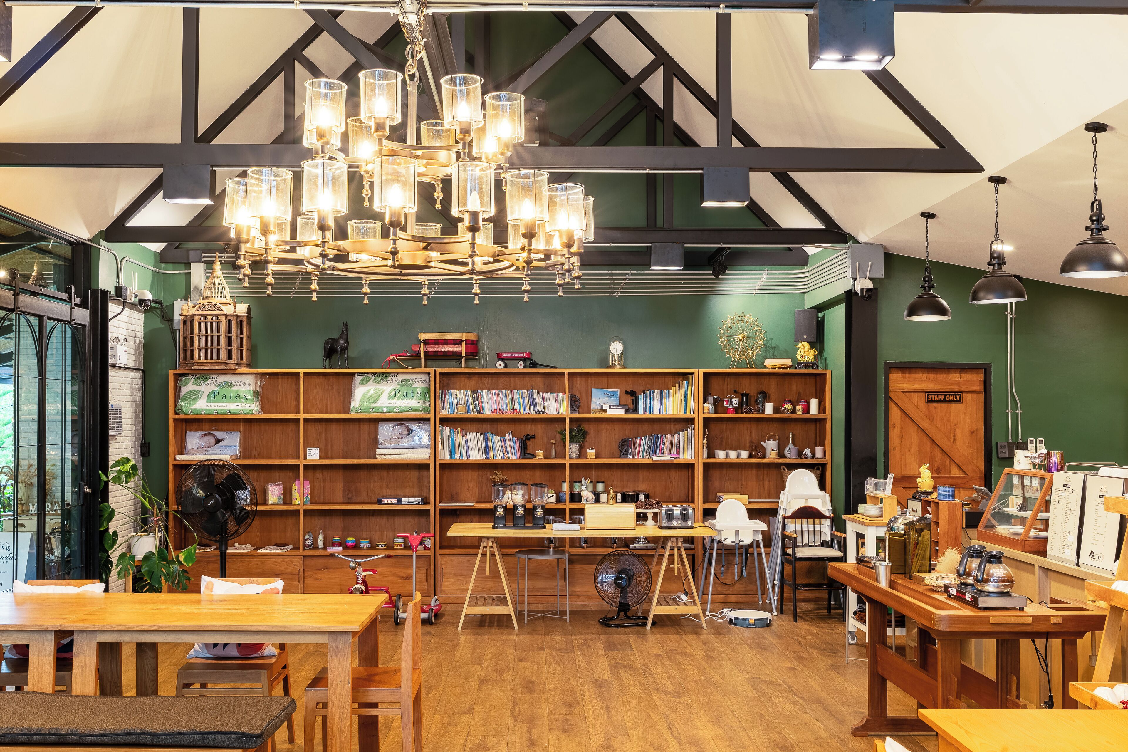 A cozy bookstore with wooden shelves, a large fan, and a chandelier.