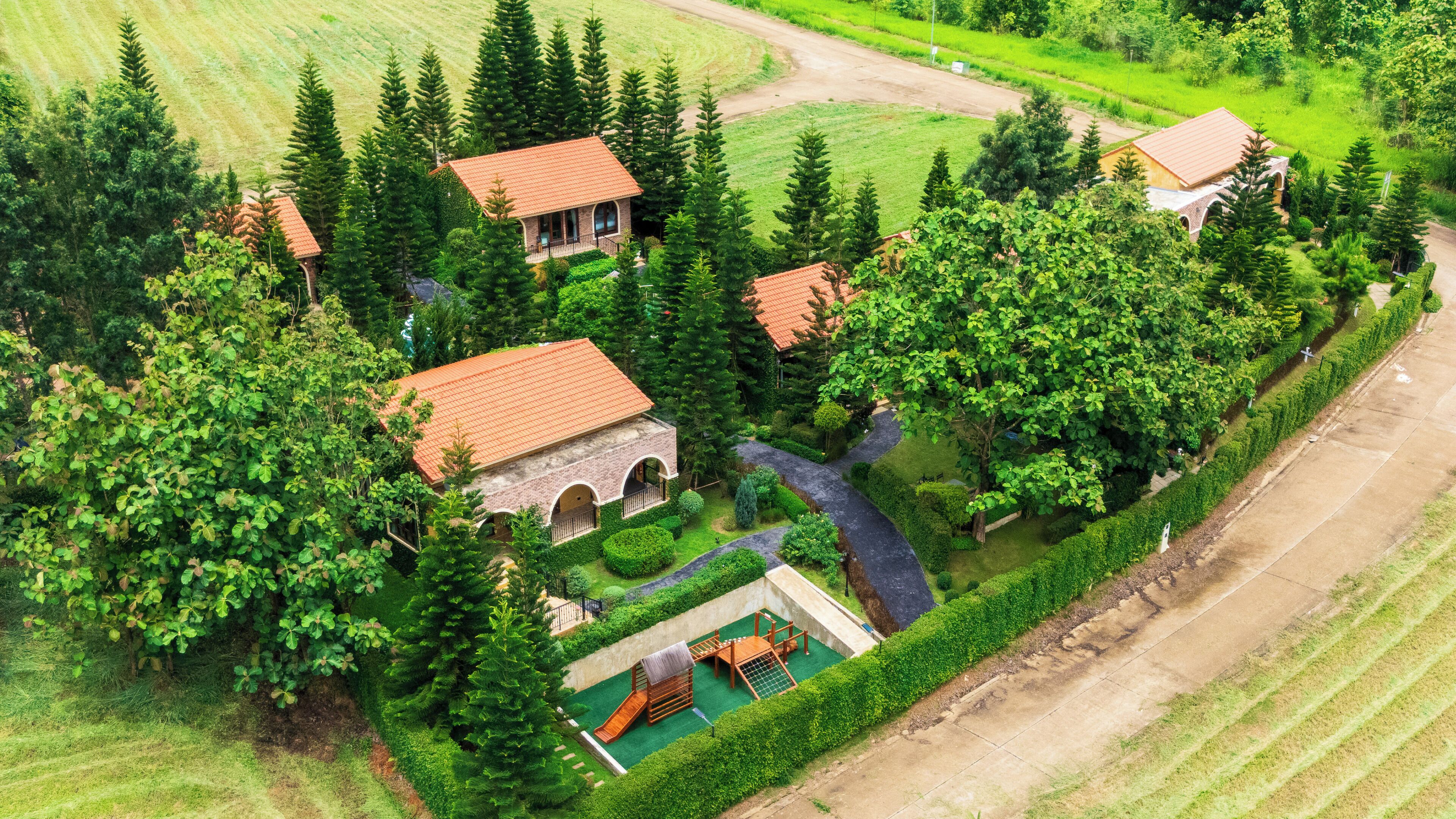 An aerial view of a property with multiple buildings, a well-maintained garden, and a playground.