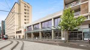 A modern building with a glass entrance and a tram line nearby. - Central Art-deco 1bed With Balcony Aircon (Sydney)