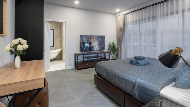 Une chambre à coucher moderne avec un grand lit, une table de chevet et un téléviseur.
