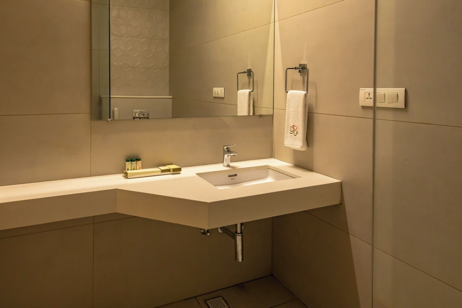A modern bathroom with a white sink, a mirror, and a towel rack.