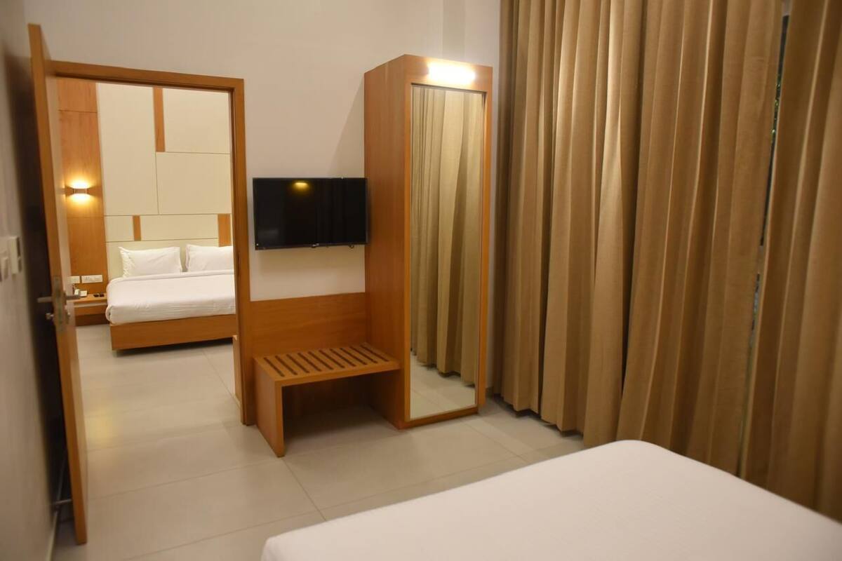Una habitació d'hotel amb un llit, una taula de nit, un televisor penjat a la paret i una cortina.