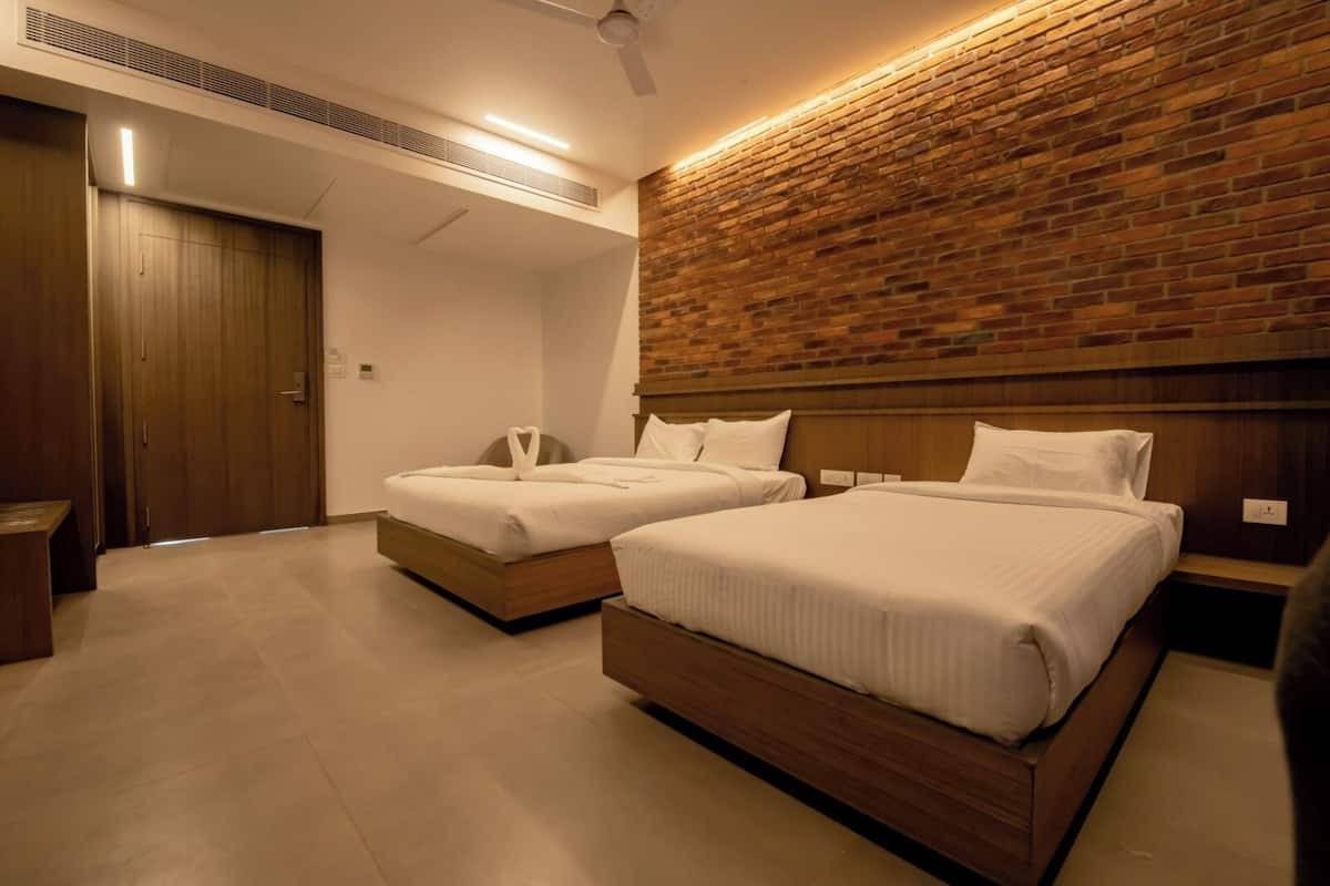 Habitació d'hotel amb dos llits, un panell de fusta al capçal, una paret d'accent de rajola i un ventilador de sostre.