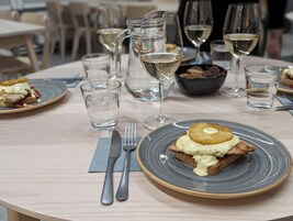 Una mesa de comedor con platos de comida, vasos de agua y una jarra de vino blanco.