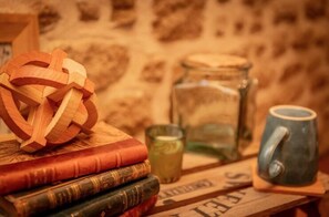 A stack of books, a wooden puzzle, a glass jar, and a mug on a wooden surface. - Les Gîtes Romeline (Sartilly-Baie-Bocage)