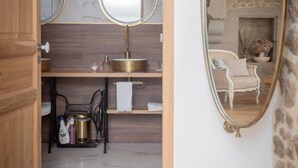 A bathroom with a vanity, a mirror, a sink, and a small window. - Les Gîtes Romeline (Sartilly-Baie-Bocage)