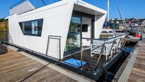 A modern boat with a white exterior, glass windows, and a deck area.
