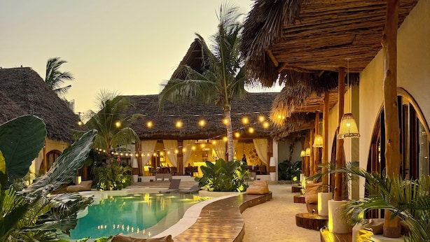 Een resort met een zwembad, rieten daken en buiten zitgedeeltes.