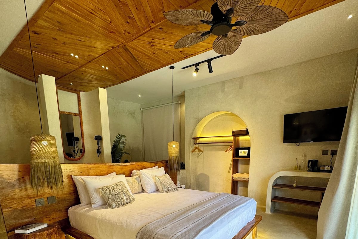 Une chambre spacieuse avec un grand lit, un plafond en bois et un ventilateur de plafond.