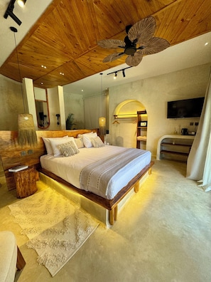 Ein geräumiges Schlafzimmer mit einem großen Bett, Holzbalkendecke und Deckenventilator.