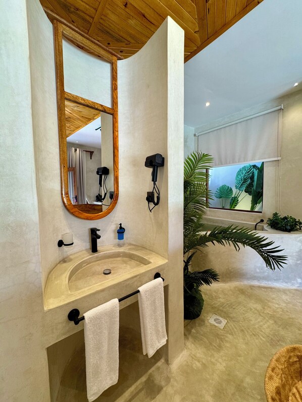Un baño con techo de madera, un espejo grande, un lavabo con grifo y un perchero para toallas.