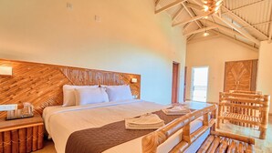 A large bed with a wooden headboard, a bedside table with a lamp, and a wooden chair. - AJ Gable clouds Ooty by VOYE HOMES  (Ootacamund)