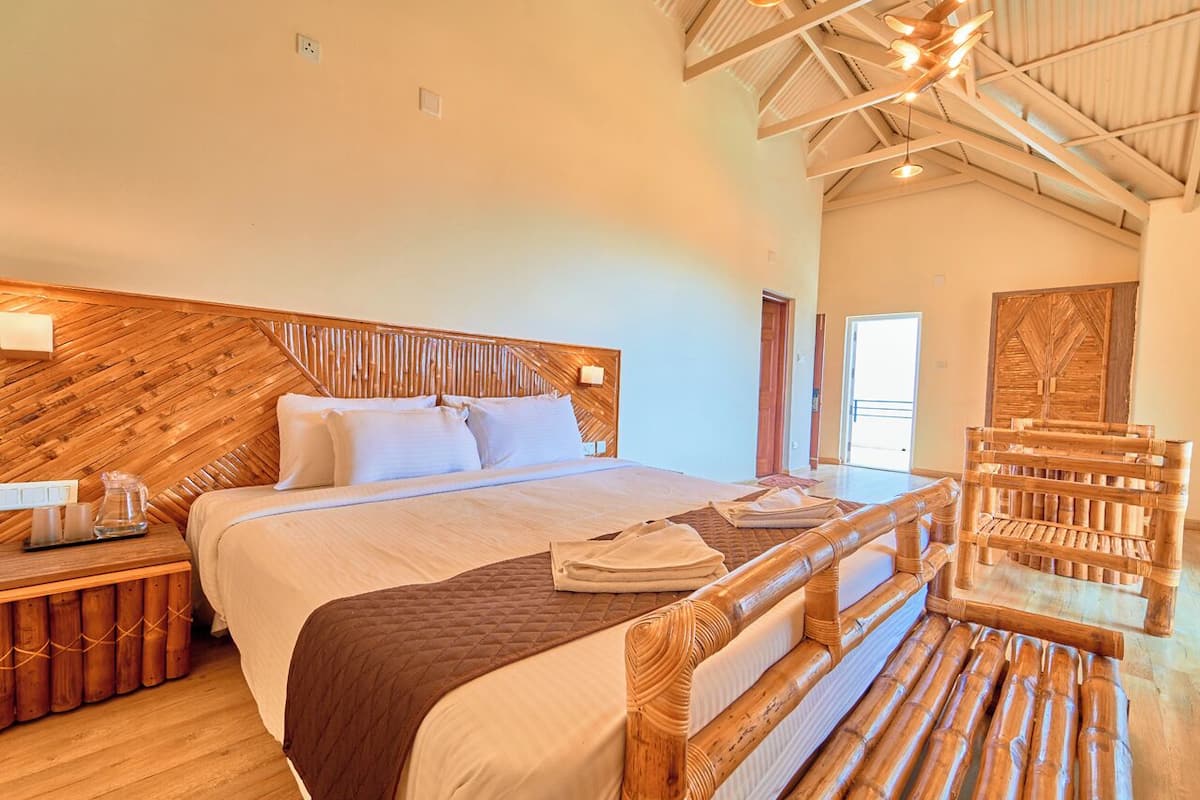 A large bed with a wooden headboard, a bedside table with a lamp, and a wooden chair.