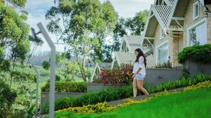 A person walking on a landscaped path with a house in the background. - AJ Gable clouds Ooty by VOYE HOMES  (Ootacamund)