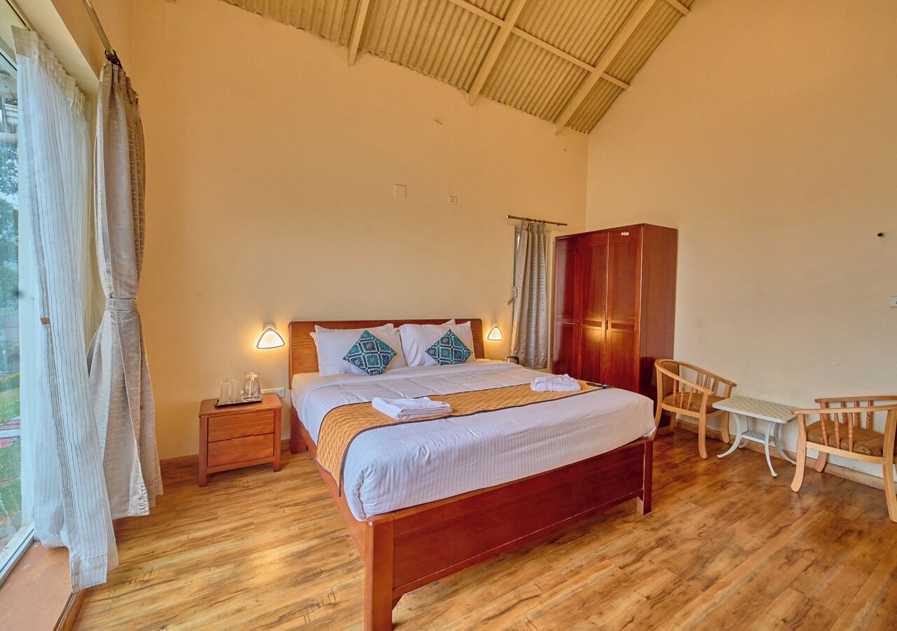 A bedroom with a wooden bed, bedside tables, a wardrobe, and a small desk with chairs.