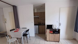 A compact living space with a dining area, kitchenette, and a small seating area. - Le Coin du Palan Chateauroux Hyper Centre (Chateauroux)