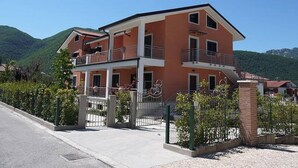 Un edificio de varios pisos con balcones, rodeado de vegetación y colinas.