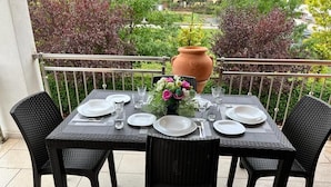 Una mesa para cuatro en un balcón con vistas a casas y árboles.