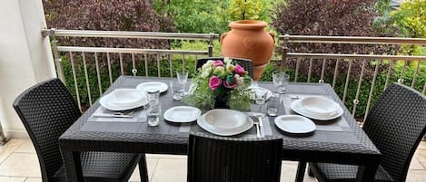 A table set for four on a balcony with a view of houses and trees.