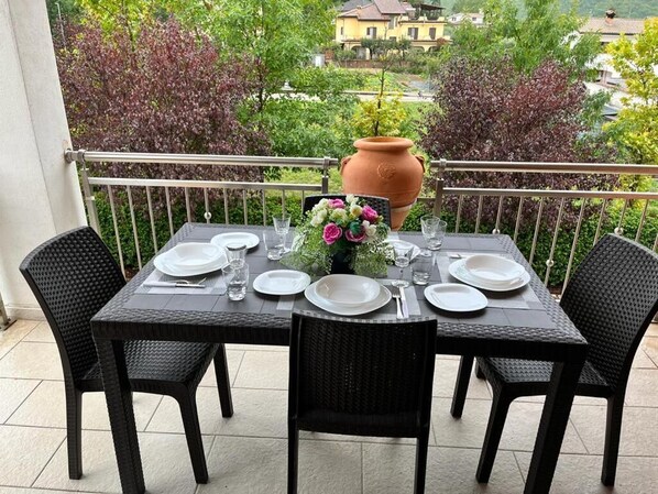 A table set for four on a balcony with a view of houses and trees.