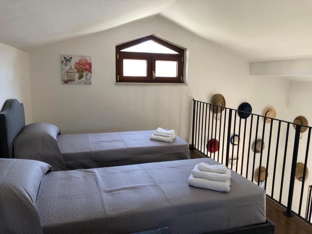 A room with two beds, a window, and a railing with hats.