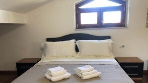 Una cama bien hecha con dos almohadas y toallas dobladas.