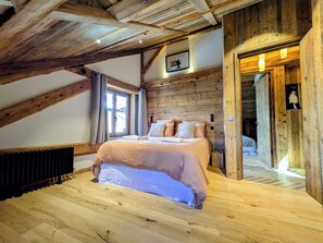 A bedroom with a wooden ceiling, a bed with a pink bedspread, and a radiator on the floor. - Nuage apartment, Megeve village center. Luxury, Art & Wellness (Megève)