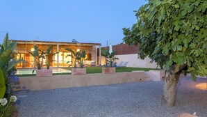 Una villa con piscina, mobiliario de exterior y un jardín bien cuidado.
