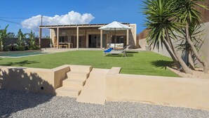 Una casa moderna con un porche cubierto, piscina y césped cuidado.