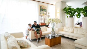 A modern living room with a sofa, coffee table, and potted plants. - Hotel Esplanade (Cesenatico)