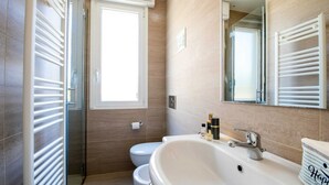 A modern bathroom with a bathtub, toilet, and a glass shower enclosure. - Hotel Esplanade (Cesenatico)