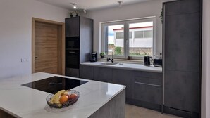 A modern kitchen with a central island, built-in appliances, and a window providing a view of the outside. - Villa for 8 people in Višnjan near Poreč (Višnjan)