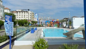 A pool area with a glass barrier, a sign listing nearby hotels, and a clear sky. - Vibe Hotel (Cattolica)