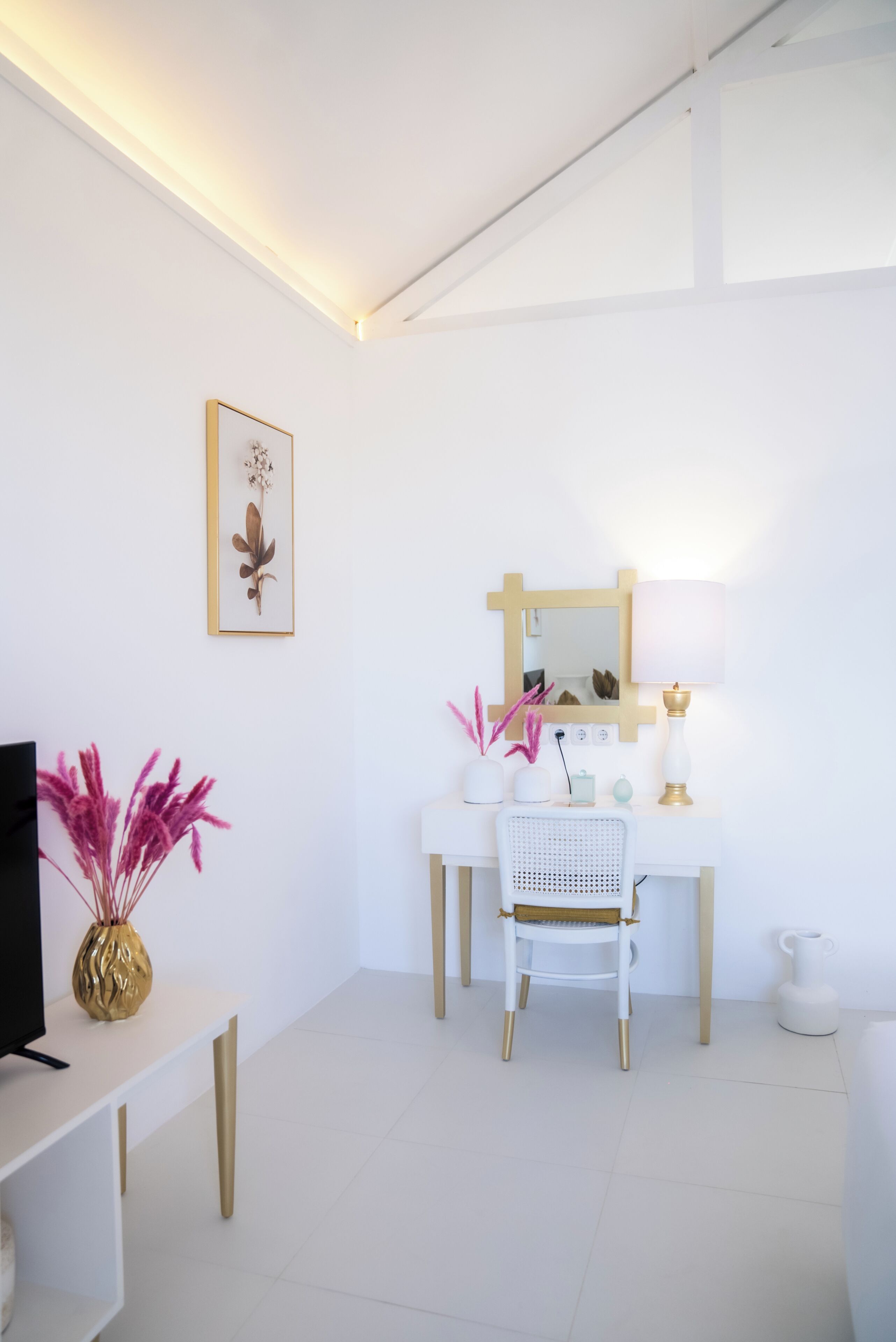Une pièce moderne et minimaliste, dotée d’un bureau blanc, d’une chaise, d’un téléviseur et d’une plante décorative.