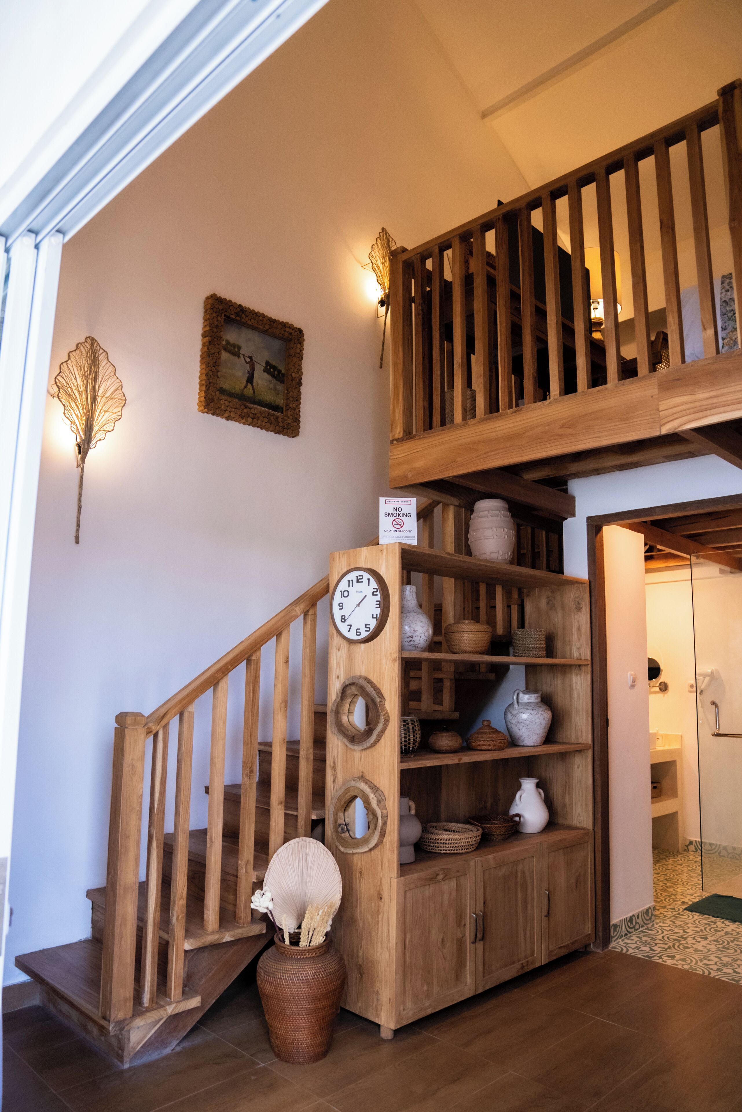 A wooden staircase with a clock and shelves of pottery.