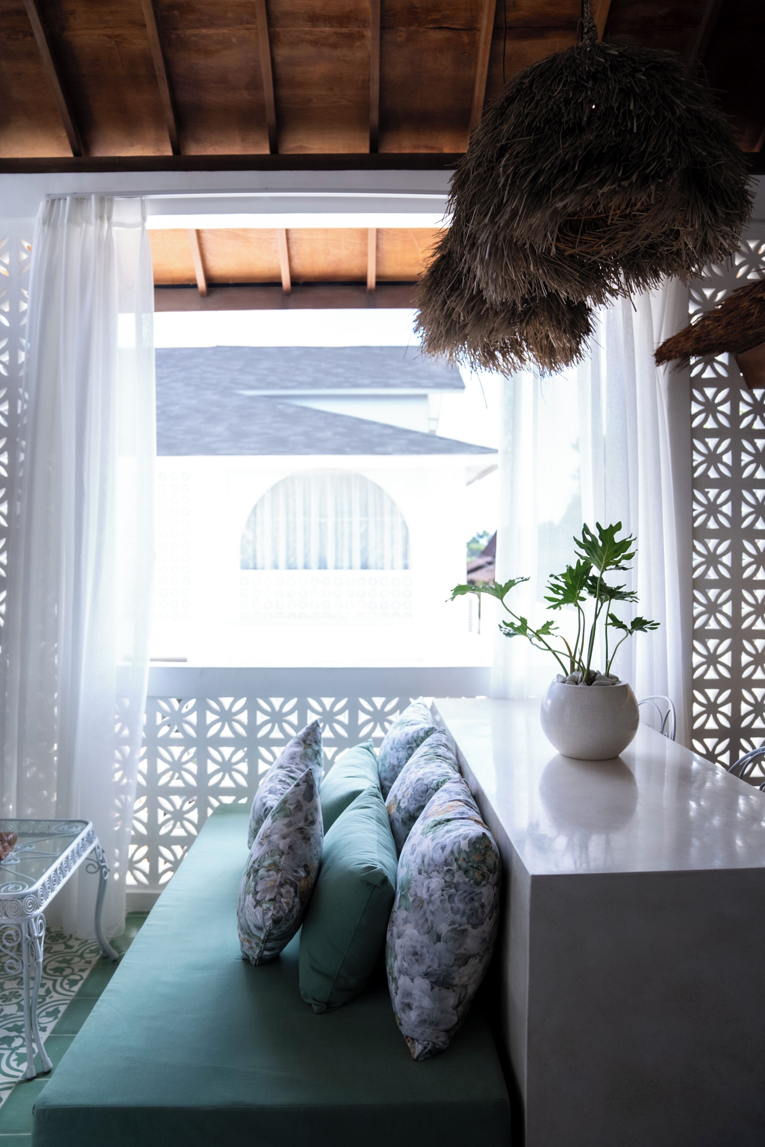 A room with a green sofa, a white table, and a hanging thatch.