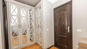 A room with a wooden floor, a dark wooden door, and a white wardrobe with glass panels. - The Expert (Cairo)
