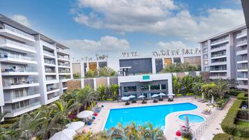 Un hotel moderno con piscina central rodeada de zonas de descanso y vegetación.