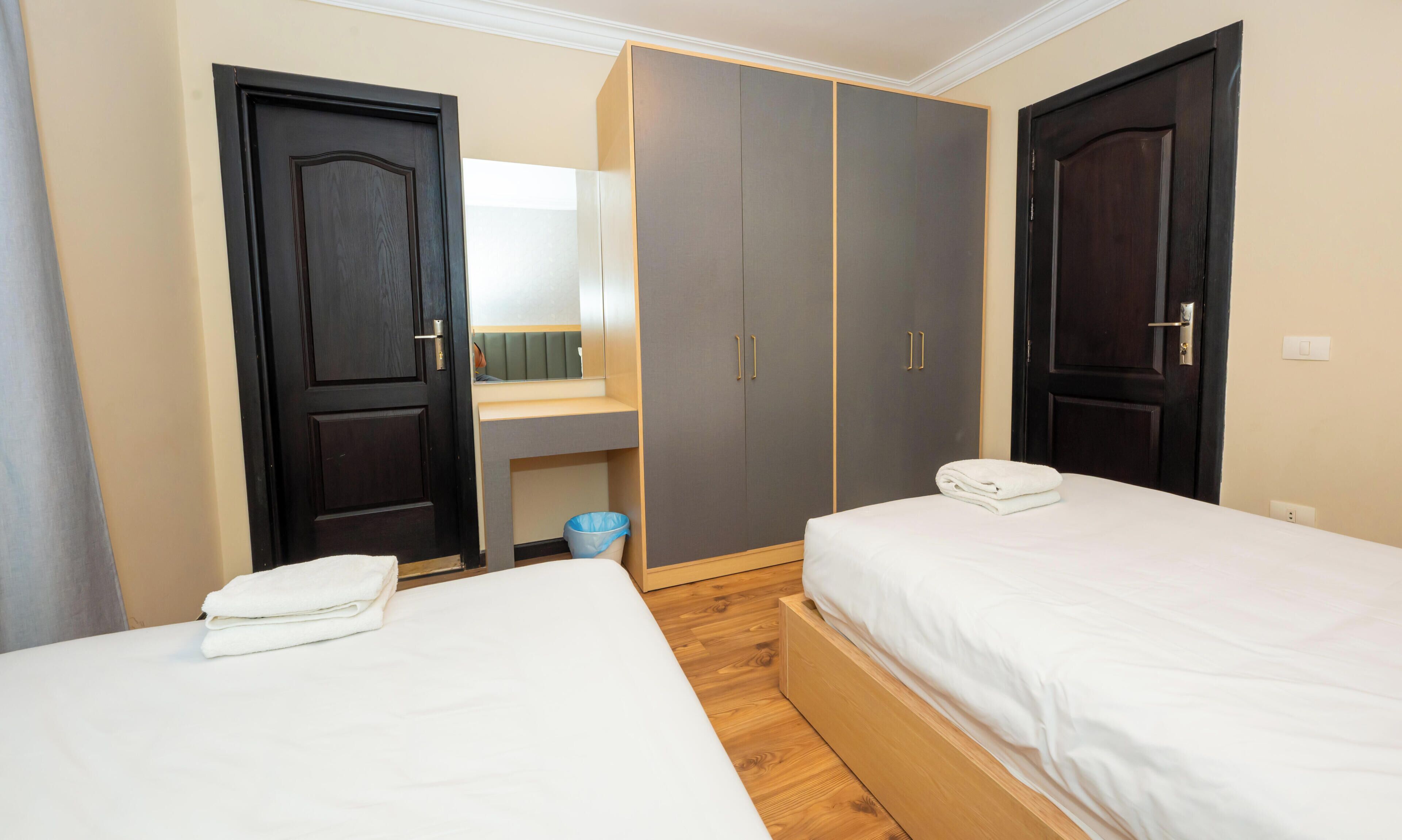 Une chambre d’hôtel avec deux lits, un bureau et une armoire.