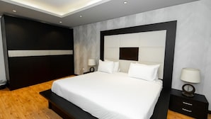 A modern bedroom with a large bed, dark wood flooring, and a minimalist design. - The Expert (Cairo)