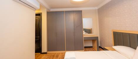 Habitación de hotel con cama, armario, espejo y baño pequeño.